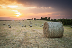 Large hay bale in a freshly harvested field beneath dramatic evening skies near Gort, County Galway.