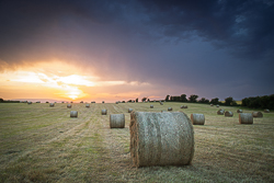 Freshly harvested field with hay bales under colourful sunset skies in County Galway.